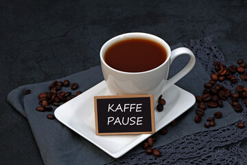 Vor einer Tasse Kaffee steht ein Schild mit der Aufschrift Kaffeepause.