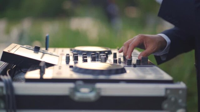 Close-up of a man's hands playing music with a DJ during the wedding reception party.