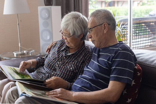 senior couple watching photo album  together on couch at home