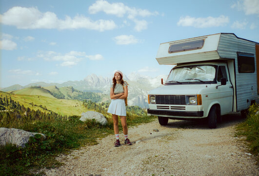 Woman standing near the old camper van during road trip in Alps