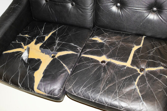 Broken leather sofa with cracks and holes with hard direct flashlight