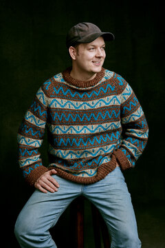 a nordic man wearing a knitted sweater, jeans, and a cap.
