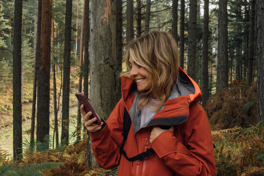 Young Woman Hiker Using Mobile Phone in Forest