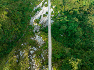 Aerial view of a Tibetan suspended bridge in Nepal is a primitive type of bridge in which the deck lies on two parallel load-bearing cables that are anchored at either end. Wild nature - 777643270