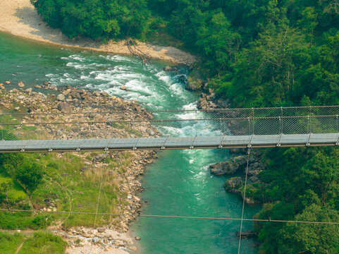 Aerial view of a Tibetan suspended bridge in Nepal is a primitive type of bridge in which the deck lies on two parallel load-bearing cables that are anchored at either end. Wild nature