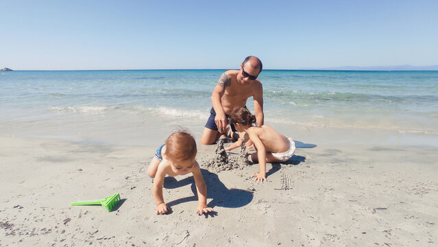  dad and kids building sandcastles on the beach