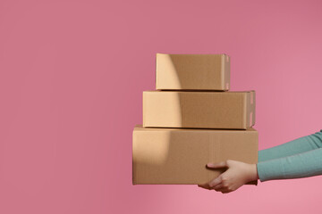 Delivery handing parcel box to recipient on pink background