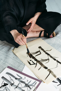 Unrecognizable Female Creating Drawings in Japanese style.