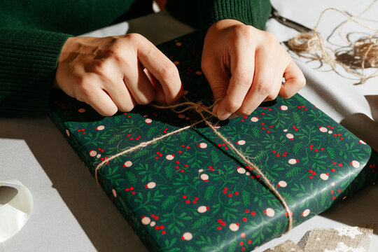 Person Wrapping Gift In Green Paper.