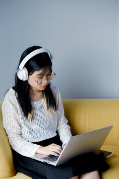 Young office worker wearing headset and using laptop on sofa