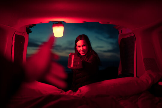 Happy travellers sharing a drink in camper van at night