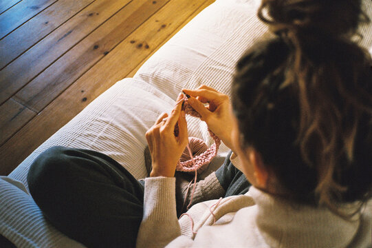 Anonymous young woman knitting on the couch