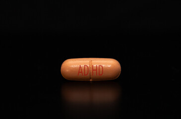 Close-up with a medication pill with the inscription ADHD on a black background. ADHD medication