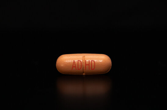 Close-up with a medication pill with the inscription ADHD on a black background. ADHD medication