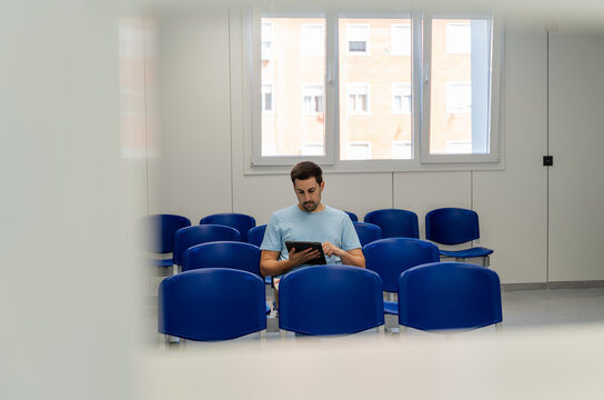 man sittingin a wait room and using a digital Tablet