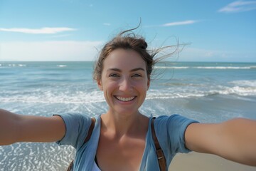 Happy woman with arms outstretched taking a selfie enjoying freedom at the beach