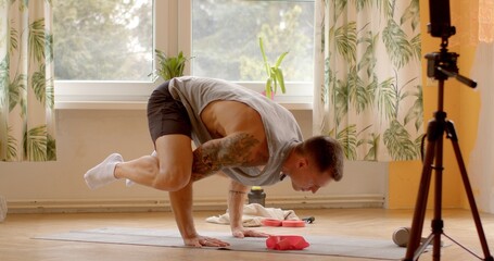 Young man video blogger demonstrates and performs physical exercises at home. Balance parenting responsibilities with maintaining a healthy lifestyle. Incorporating exercise into daily
