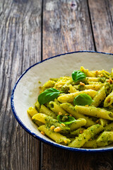 Penne with basil pesto sauce on wooden table
