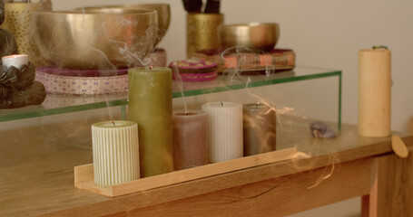 Singing bowls are used to create sounds that promote relaxation. Smoke of extinguished candles marks the end of session. Woman woman blowing out candles after singing bowl and energy healing session.