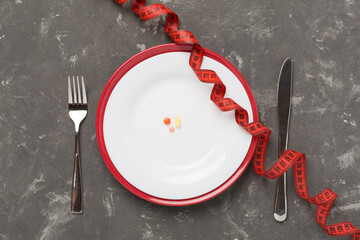 Measuring tape with empty plate on concrete background, top, view. Weight loss concept