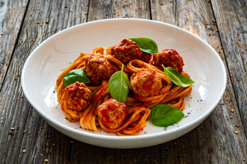 Spaghetti meatballs in tomato sauce on wooden table 