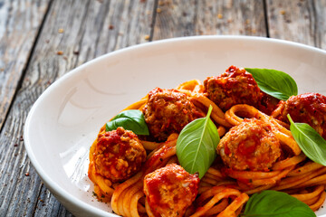 Spaghetti meatballs in tomato sauce on wooden table 