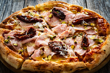 Pizza mortadella with mozzarella cheese and sun dried tomatoes on wooden table
