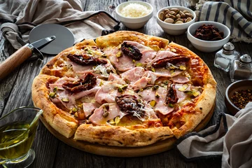 Fototapeten Pizza mortadella with mozzarella cheese and sun dried tomatoes on wooden table  © Jacek Chabraszewski
