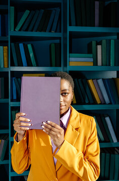 Woman hiding half of face behind book 