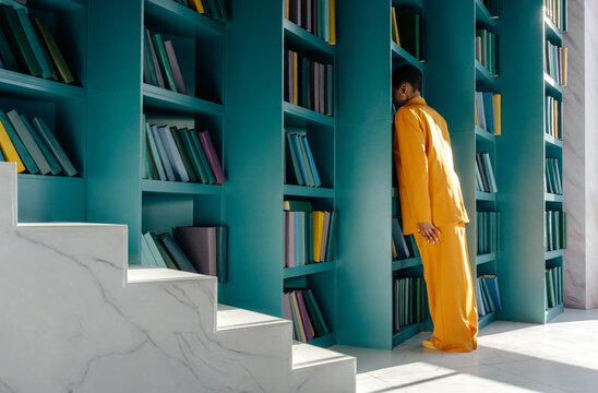 Anonymous woman leaning head on bookshelf in library