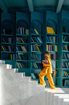 Person in formal suit climbing on stairs in library