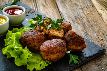 Fried meatballs on black stony plate on wooden table
