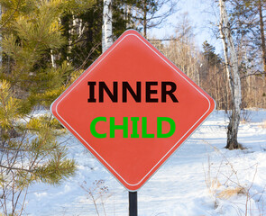 Inner child symbol. Concept words Inner child on beautiful red road sign. Beautiful forest snow blue sky background. Psychological, motivational inner child concept. Copy space.