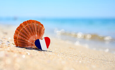 Sandy beach in France. Flag of France in the shape of a heart and a large shell. A wonderful...