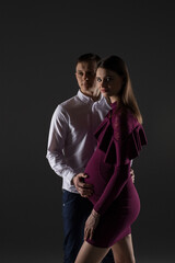pregnant couple stands on a grey background, studio pregnancy shoot, fashion pregnancy, portrait of a couple, pregnancy, pregnant