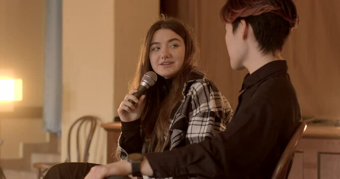 students engage in discussions and debates. Support and encouragement for students active participation Woman, leading the event, applauds with the microphone in hand during school parliament session