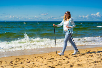 Nordic walking - beautiful woman exercising on beach
