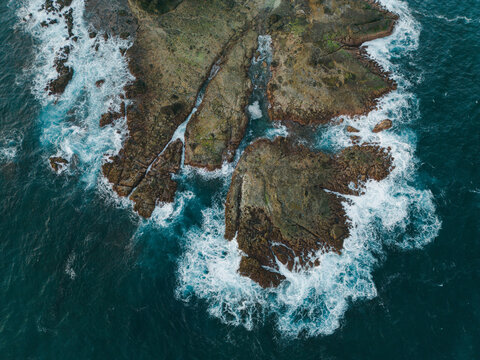 Aerial view of waves crushing on rocks  