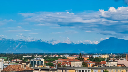 Naklejka na ściany i meble Aerial panoramic view of historic city of Udine, Friuli Venezia Giulia, Italy, Europe. Viewing platform form castle of Udine. Cloudy overcast day. Distant view of mountains of Alps, border to Austria