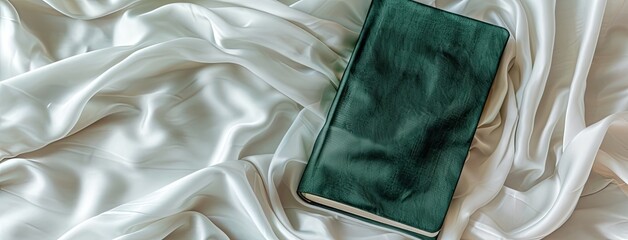 an emerald-covered diary set against a luxurious white cream silk background, exuding sophistication and style. - Powered by Adobe