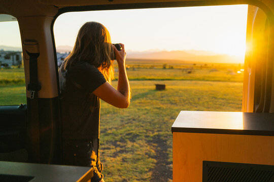 Photographer by her camper van taking a photo at sunset 