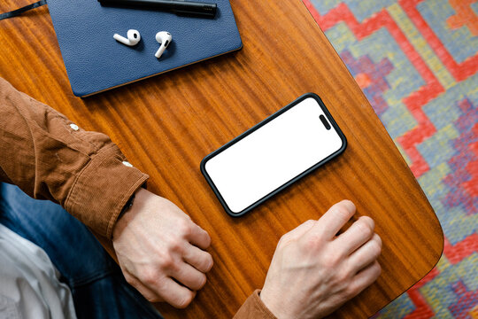 A mobile phone with white screen lies in front of a man