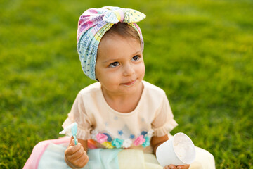 Little girl with emotions eats ice cream on the street in the park.