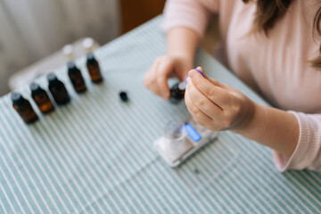 High-angle view of unrecognizable female artisan preparing using of scented perfume for creating candle building mixture. Process of making handmade natural scented candle at workshop.
