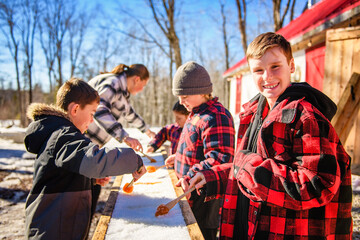 Photo showing children tasting maple syrup with wooden spoon - 777682633