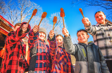 Photo showing children tasting maple syrup with wooden spoon - 777682650