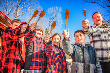 Photo showing children tasting maple syrup with wooden spoon - 777682682