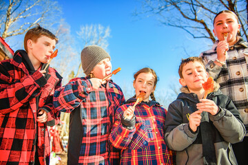 Photo showing children tasting maple syrup with wooden spoon - 777682868
