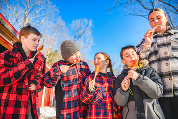 Photo showing children tasting maple syrup with wooden spoon - 777682890