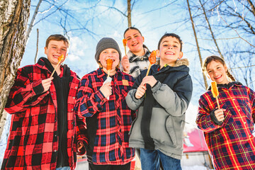 Photo showing children tasting maple syrup with wooden spoon - 777683056